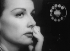 Eleanor (Ann Sheridan), listens on a telephone as she watches ahead warily, in Woman On the Run.