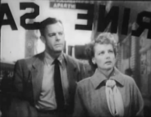 Eleanor (Ann Sheridan) looks up through a shop window as Legget (Dennis O'Keefe) watches her.